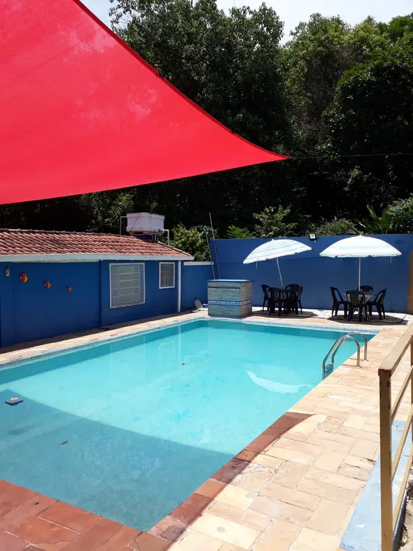 Piscina com toldo vermelho e área verde